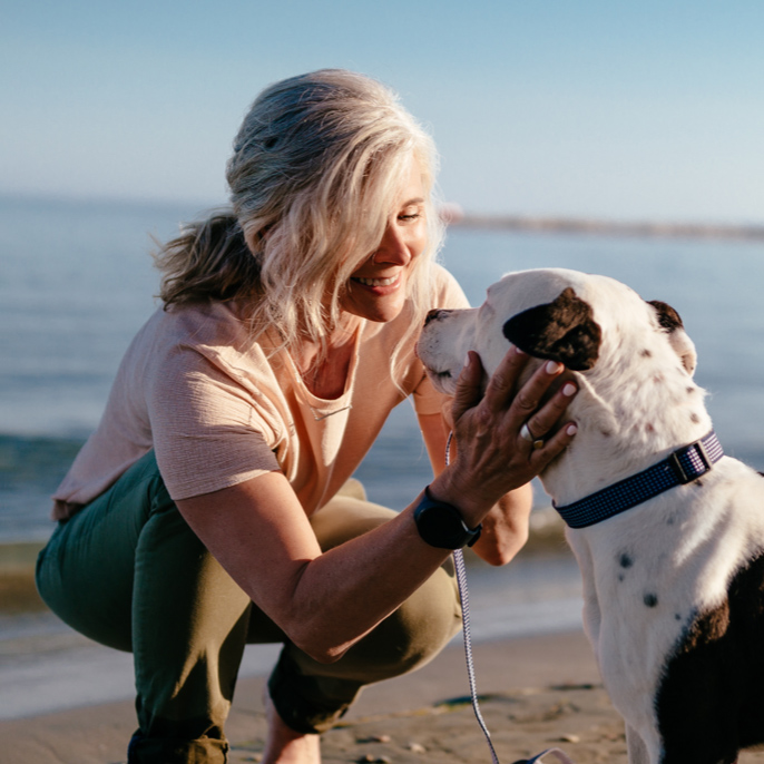 Woman with dog on beach for TruHearing How it Works Hearing Aids