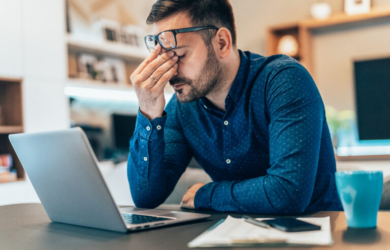 Hearing health, Tired young businessman working at home using lap top and looking Anxious
