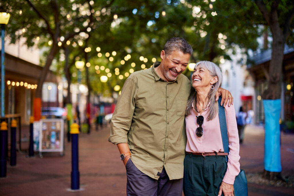 Mature couple smiling at each other and walking down an urban street
