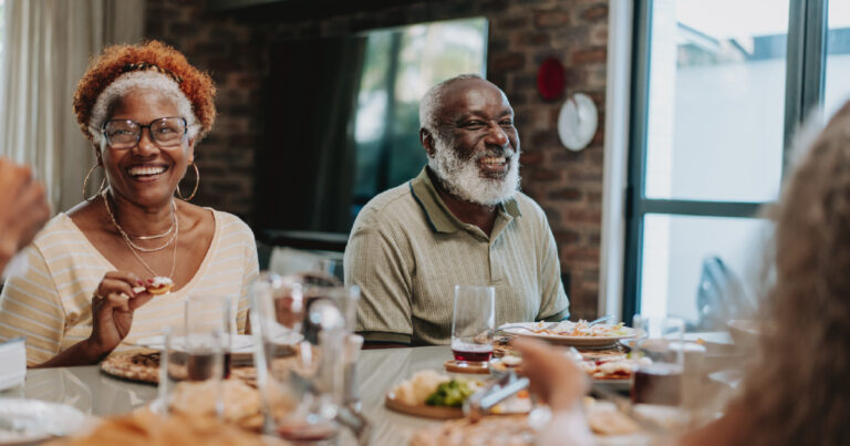 Older African American couple eating dinner with friends