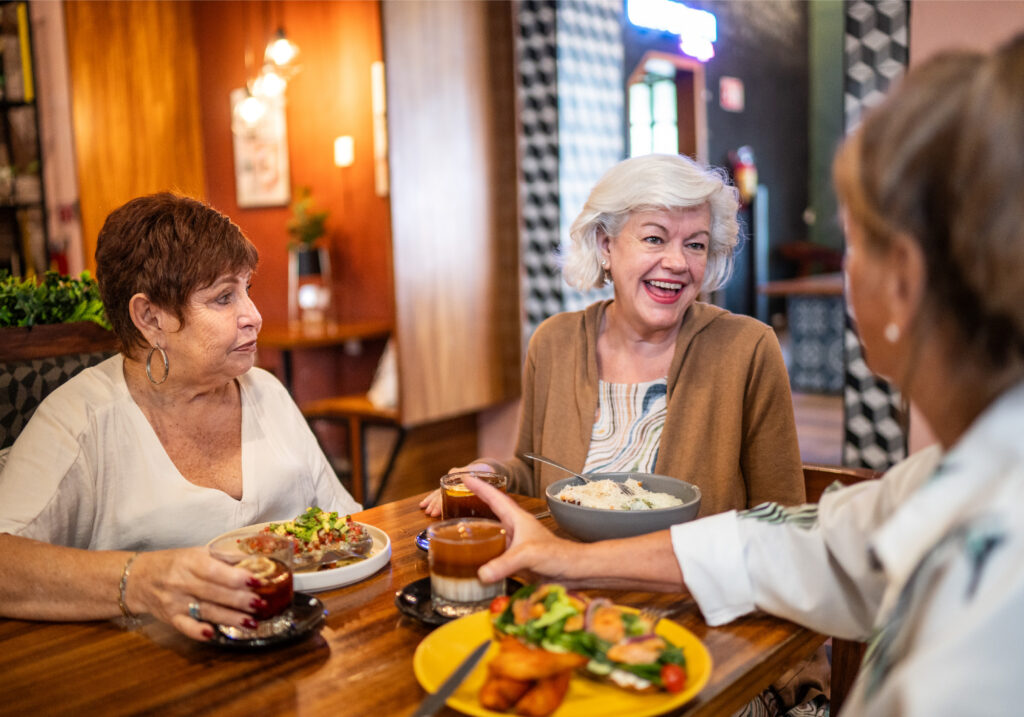Trio of older women enjoying each other's company over dinner